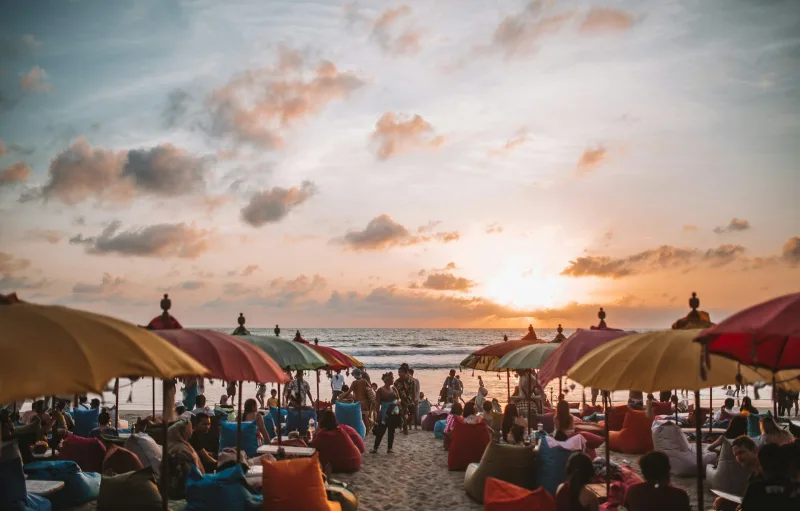 Bali beach sunset with colourful umbrellas and crowds on the sand, Seminyak beach