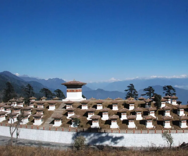 The 108 chortens at Dochula Pass, Bhutan, with the Himalayan range visible behind under a clear blue sky