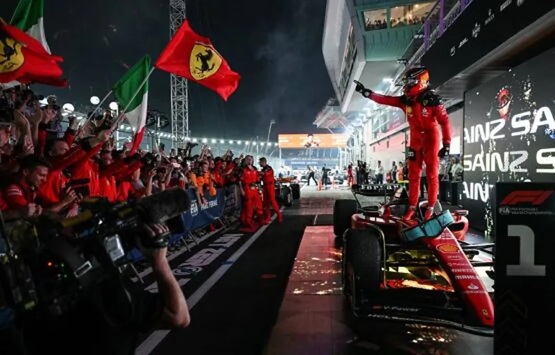 Ferrari driver standing on his car in parc ferme celebrating a win at the Singapore Grand Prix under floodlights