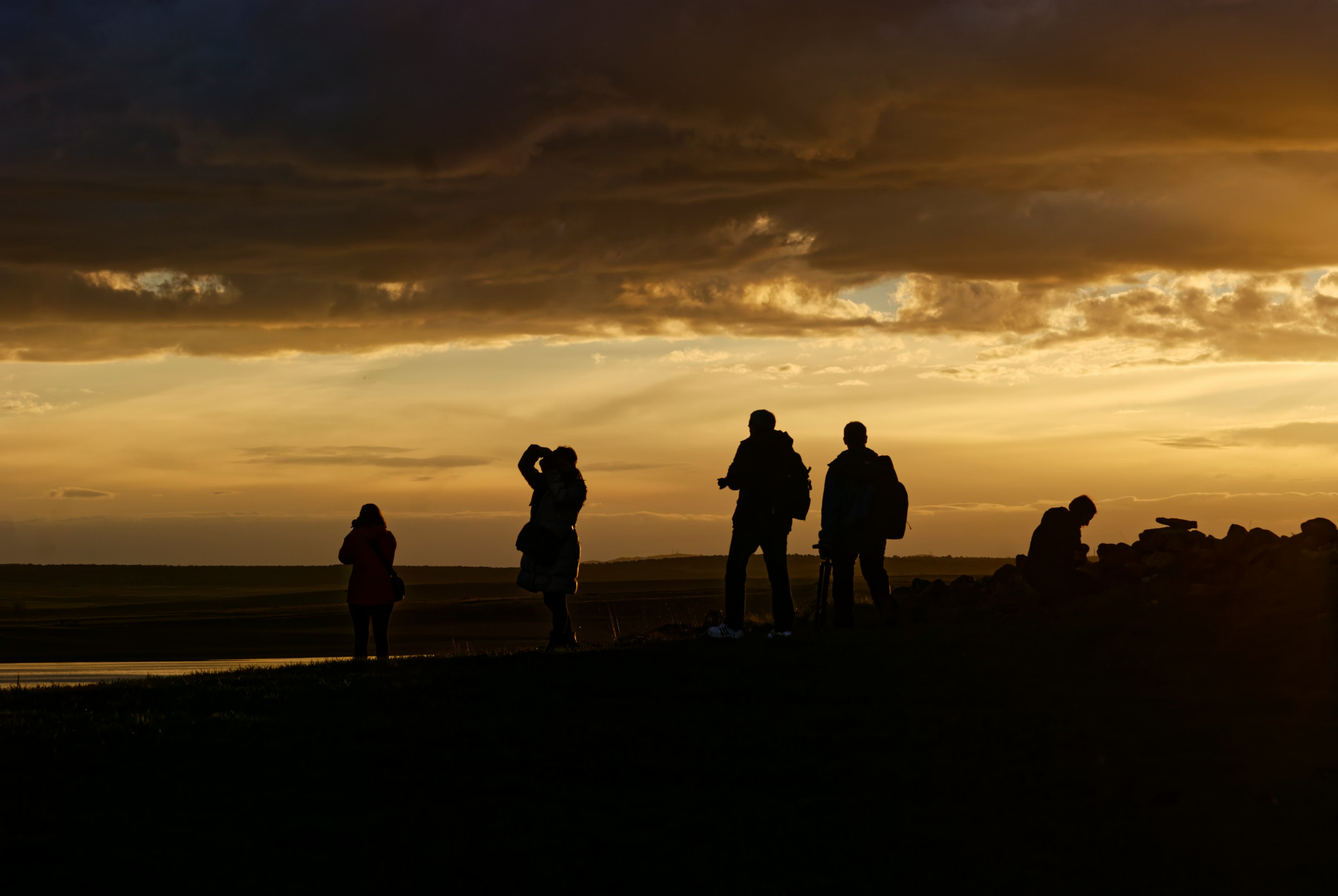 Silhouettes of trippers watching a dramatic sunset over the ocean