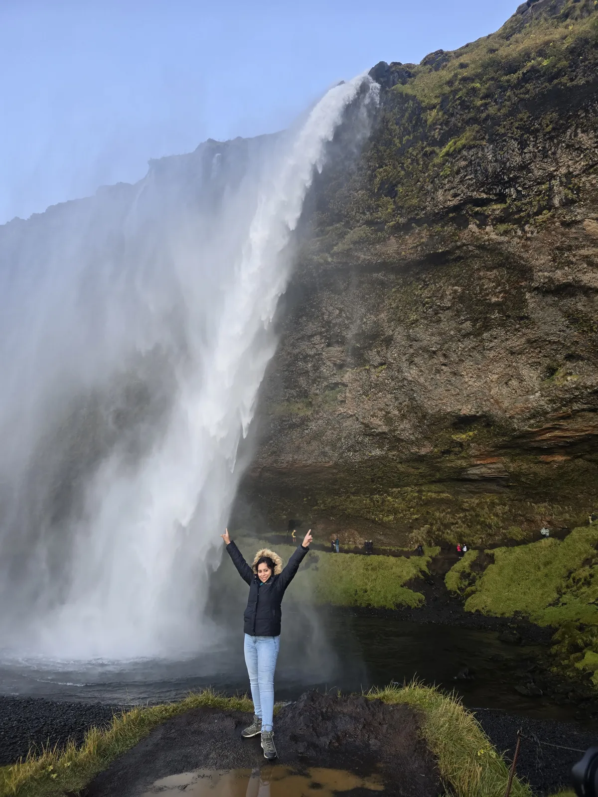 Water joyful pose on the Iceland group trip with One in the Orange Jacket.
