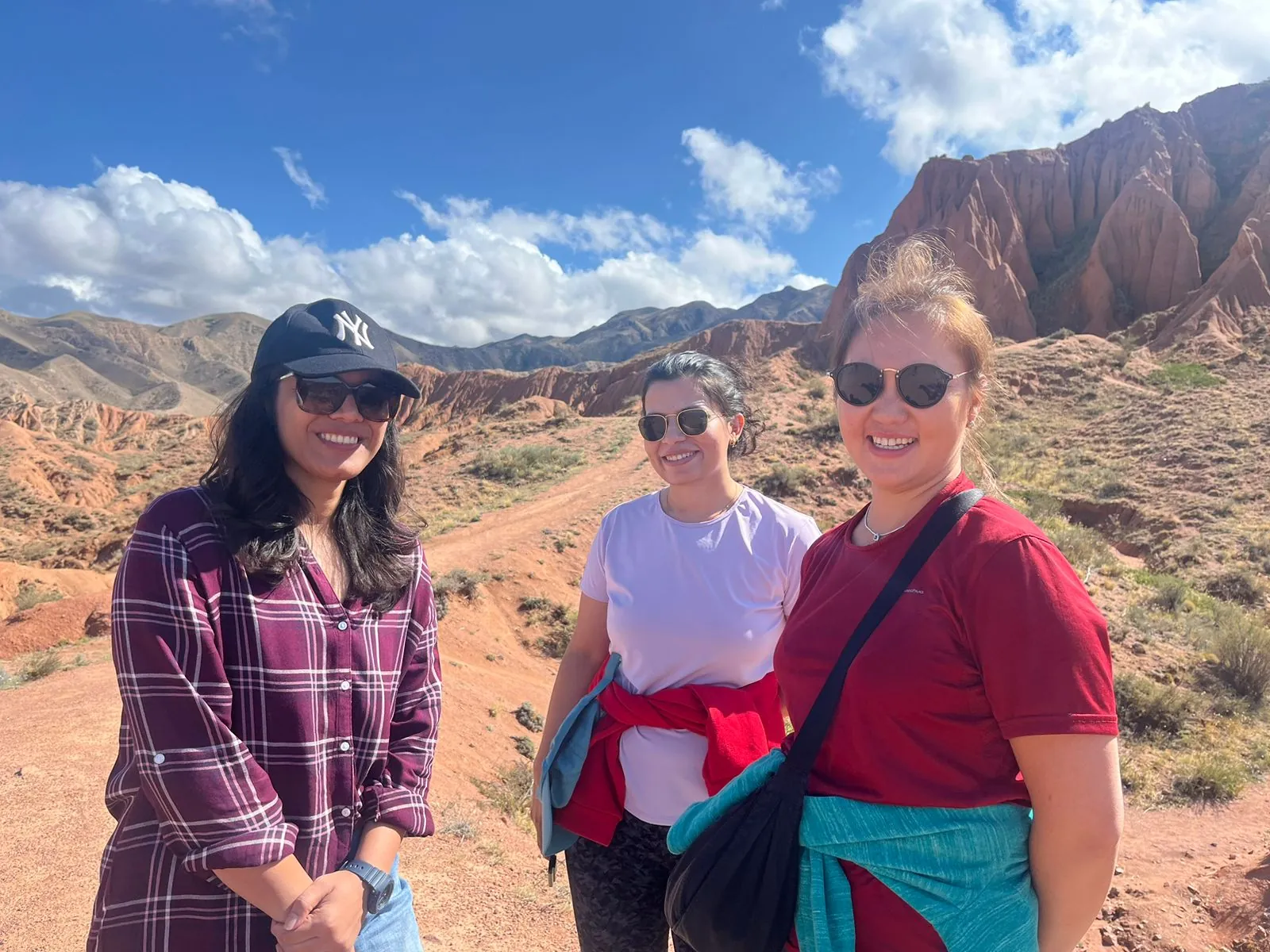 Mountain three women smiling on the Kazakhstan group trip with One in the Orange Jacket.