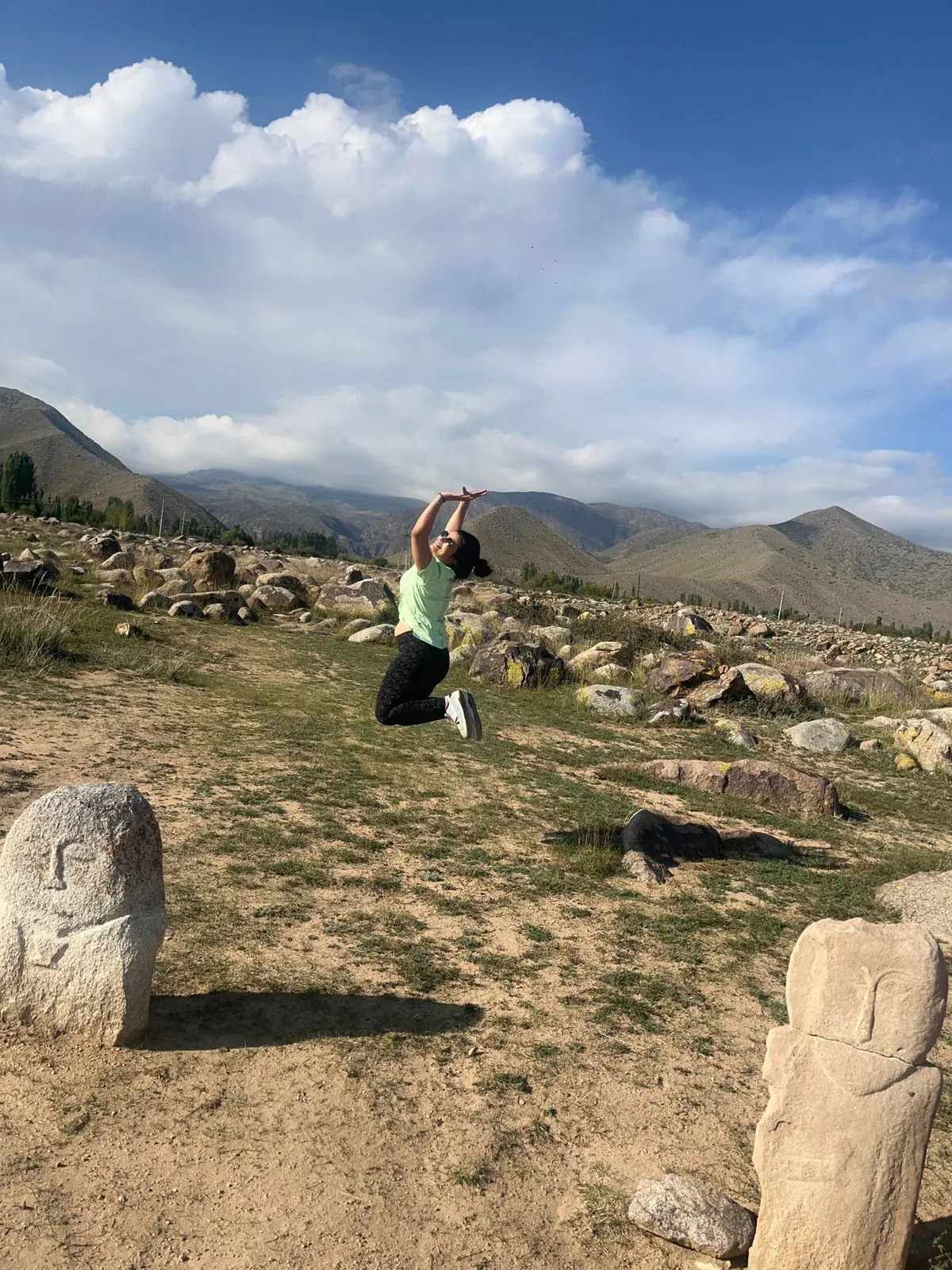 Woman joyfully jumping on the Kazakhstan group trip with One in the Orange Jacket.
