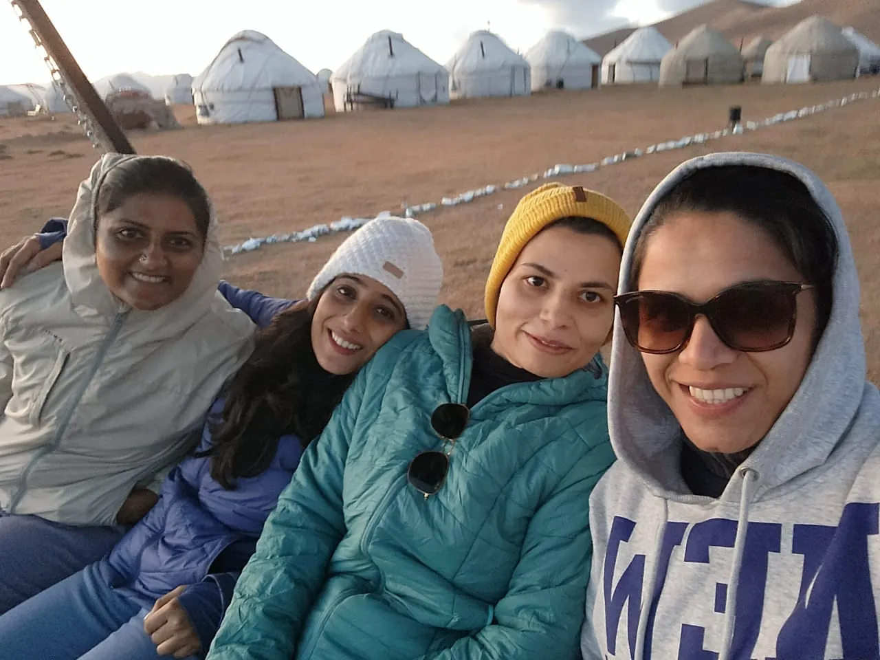 Friends smiling yurts memory on the Kazakhstan group trip with One in the Orange Jacket.