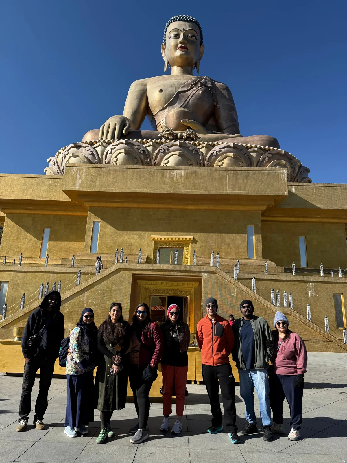 Group of trippers in front of the giant golden Buddha Dordenma in Thimphu on a clear winter day