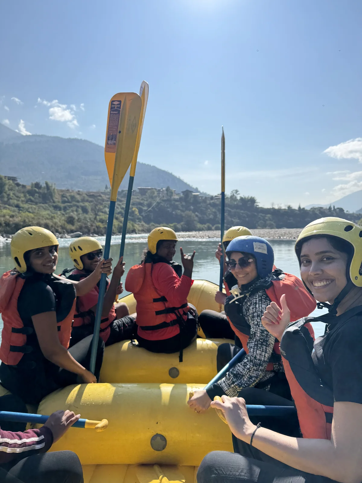 OJ group in helmets and life jackets paddling a yellow raft on the Punakha river