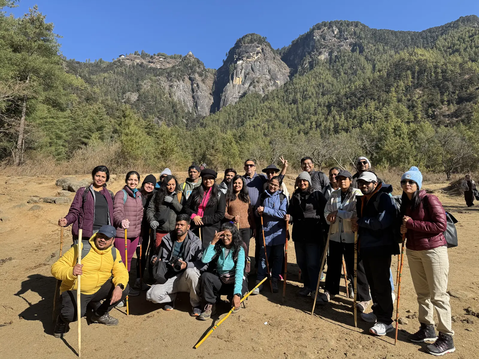 OJ group with trekking poles at the Tiger Nest trailhead under the Taktsang cliffs