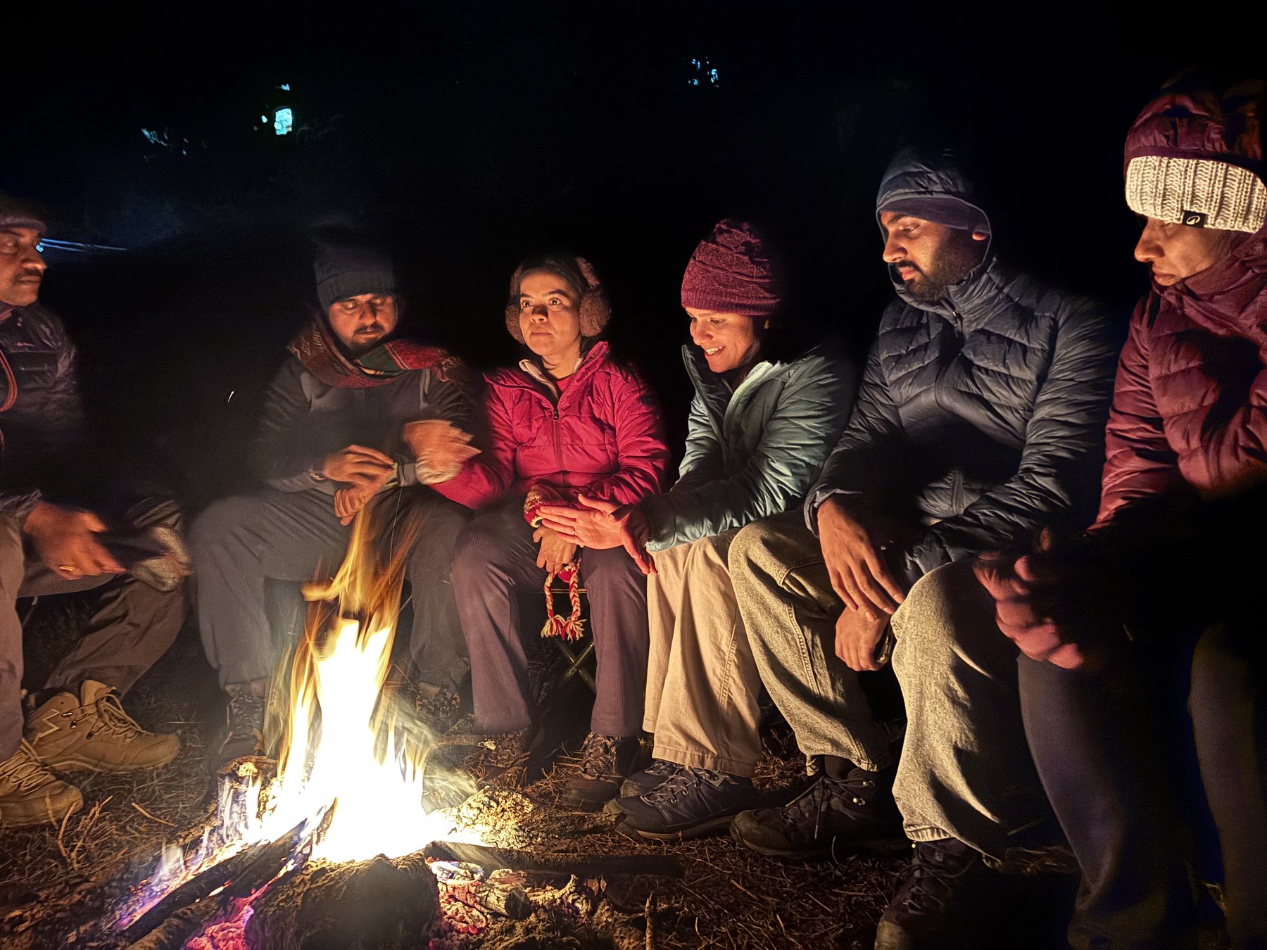 Trekkers sitting round a campfire at night at the winter camp