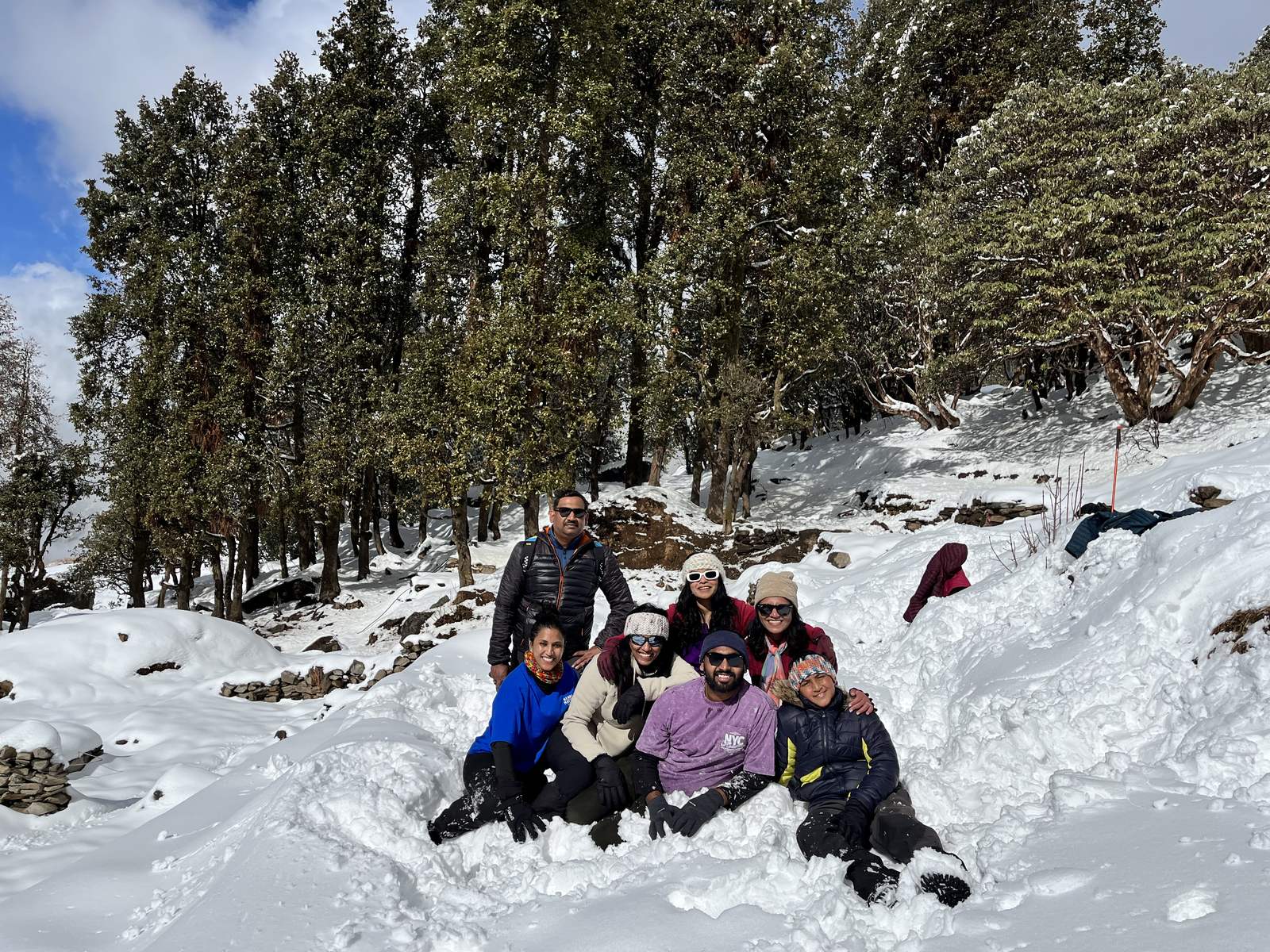 Trekkers sitting together in deep snow in a pine forest on the trail