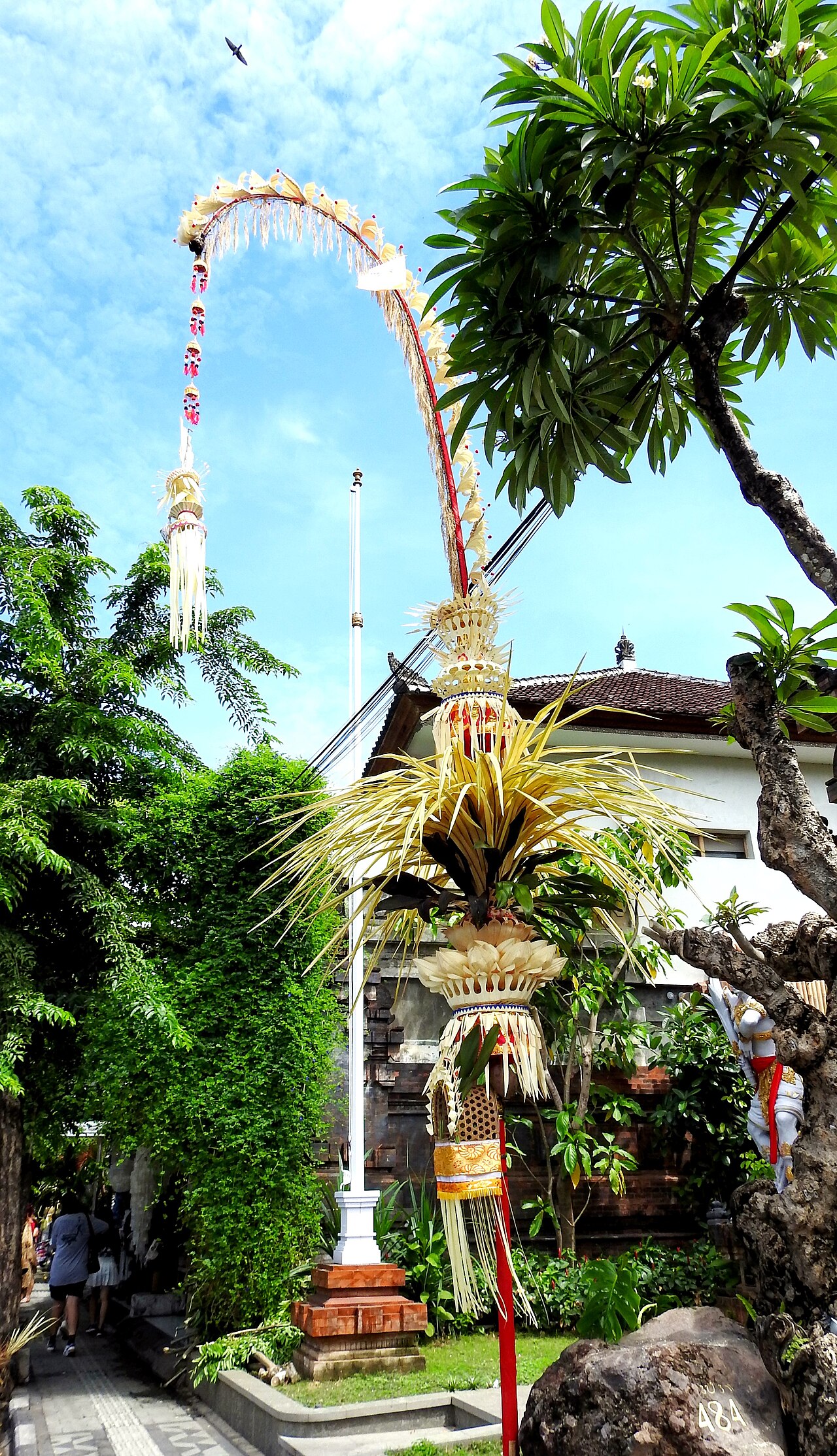 Tall decorated penjor bamboo poles lining a Balinese street during Galungan