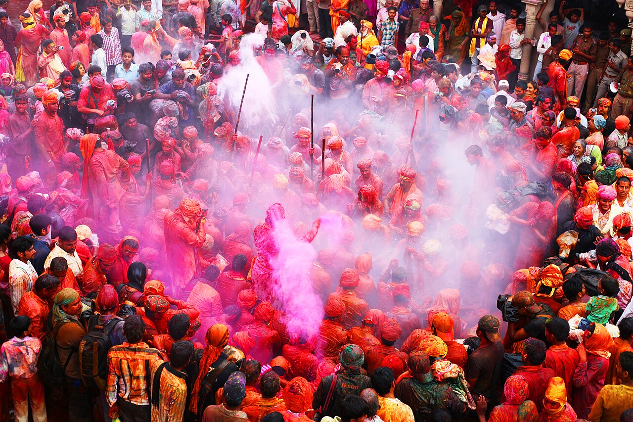 People covered in bright coloured powder celebrating Holi in India