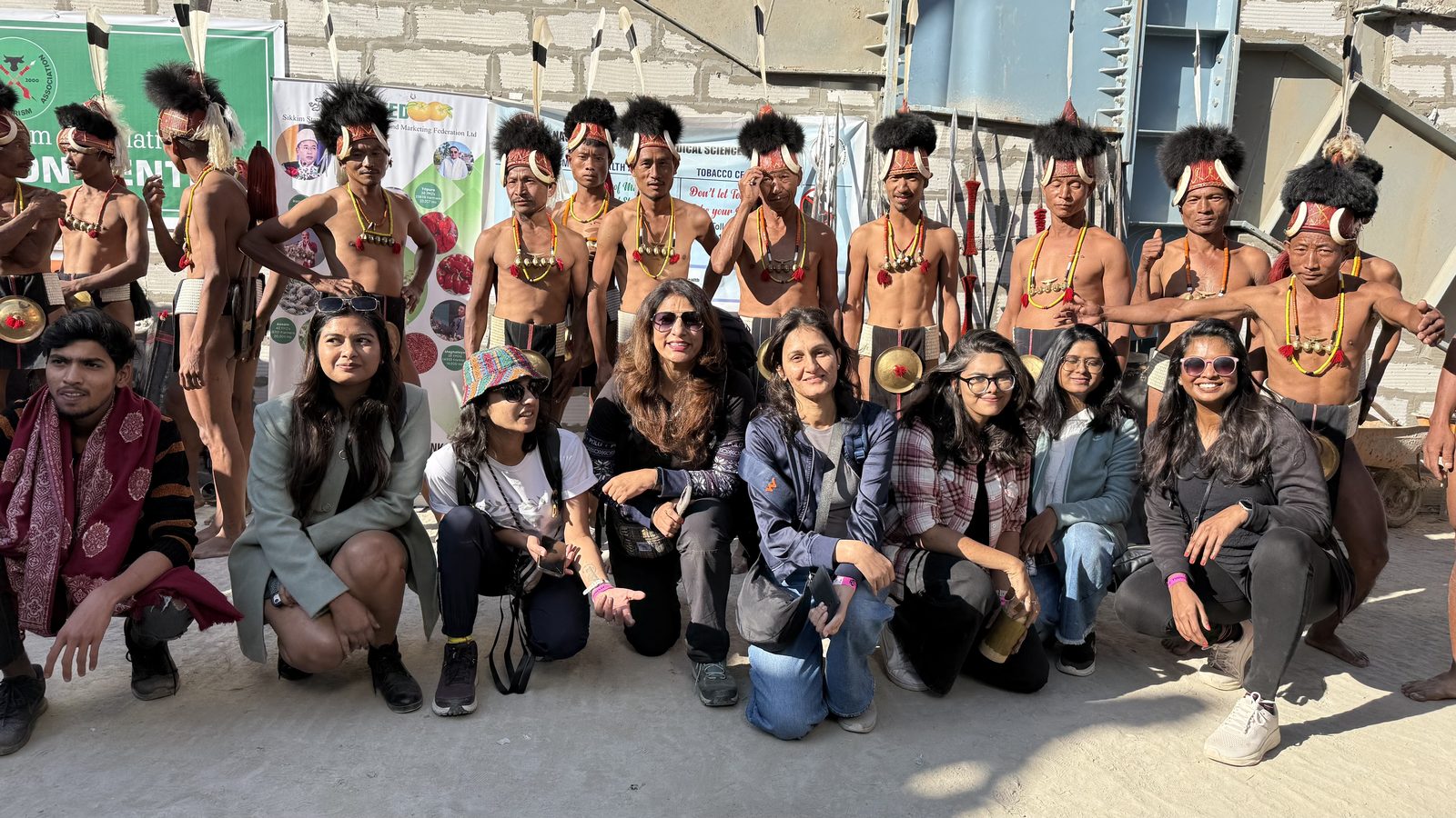 OJ group crouching for a photo with Naga warriors in traditional dress at the Hornbill Festival