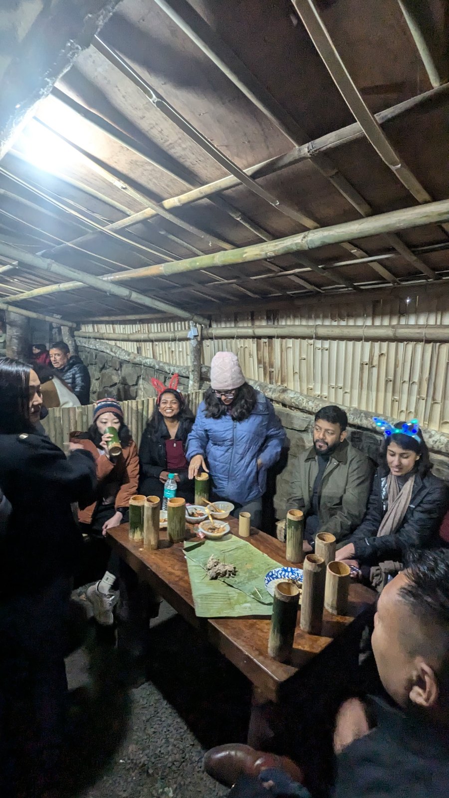 OJ group having dinner with bamboo mugs in the Dzouku camp hut