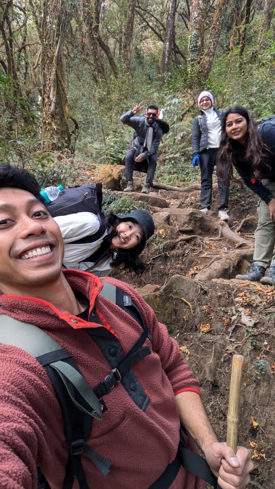 Trekker smiling on the root-covered forest trail up to Dzouku Valley