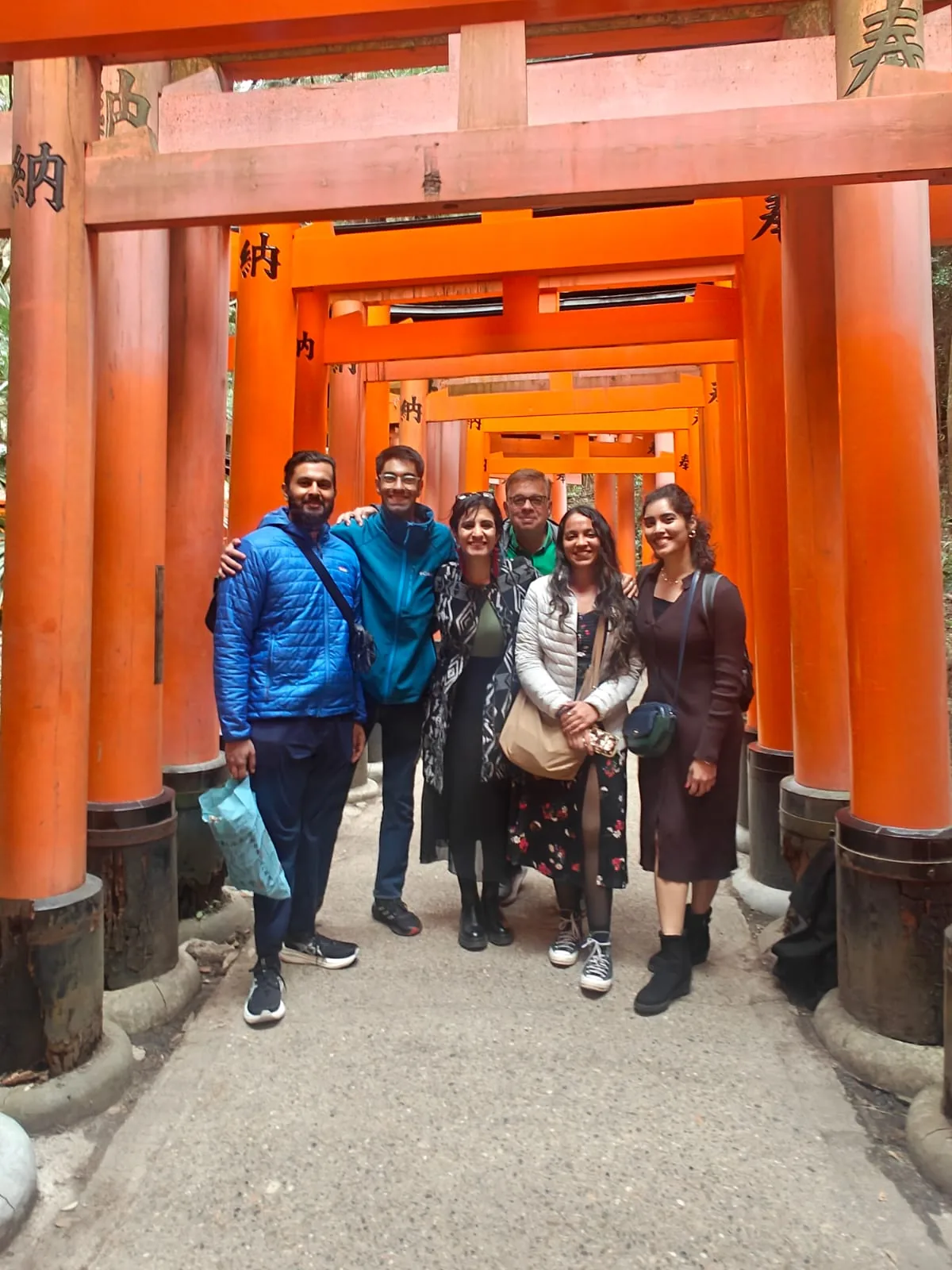 Japan, Day 6: OJ group of six smiling under the vermilion torii gates at Fushimi Inari