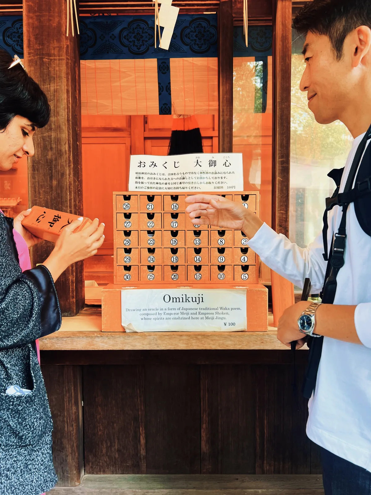 Japan Cherry Blossom, Day 4: Two trippers drawing an omikuji paper fortune at a shrine