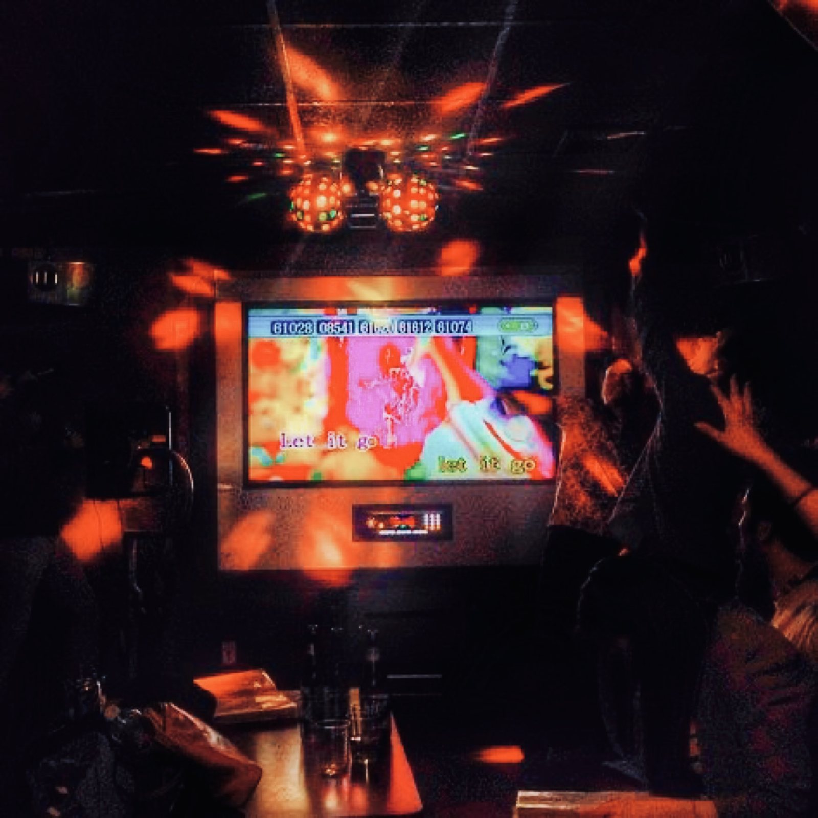 OJ trippers singing karaoke in a dim Tokyo bar with disco lights