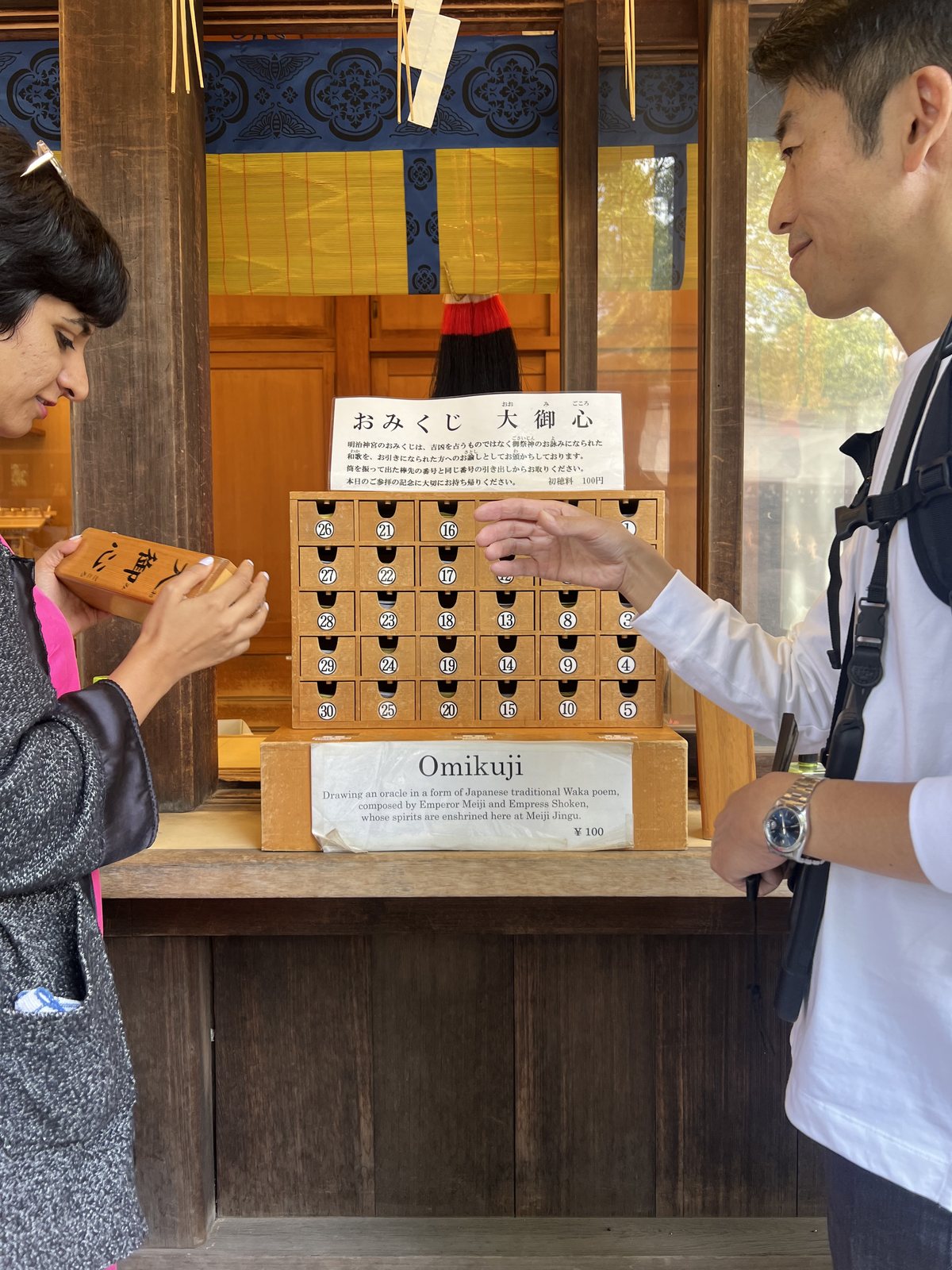 Two OJ trippers drawing omikuji fortunes at Meiji Jingu shrine in Tokyo