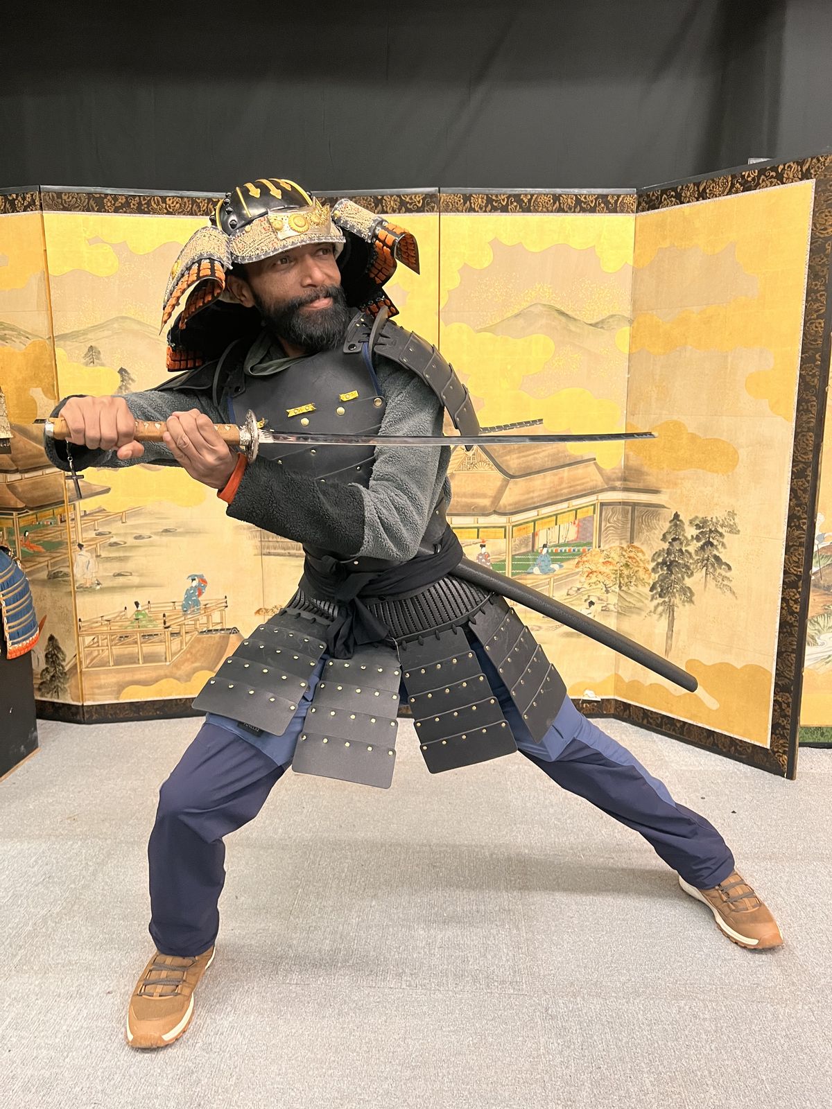 OJ tripper in full samurai armour holding a katana in front of a golden screen