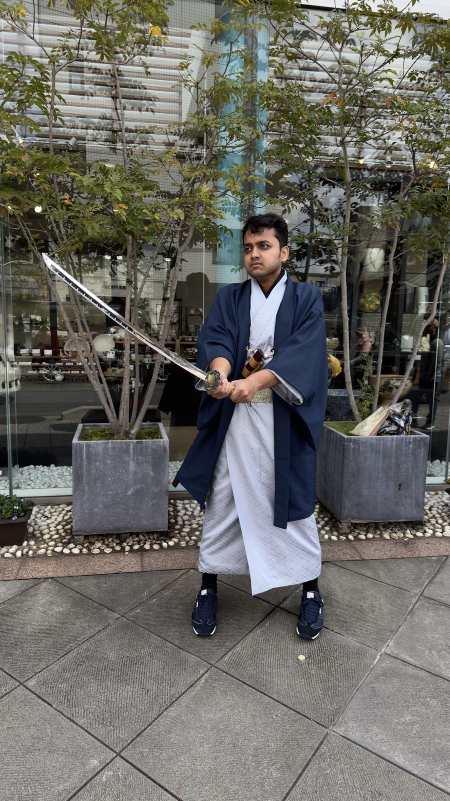 OJ tripper in kimono and hakama holding a katana outdoors