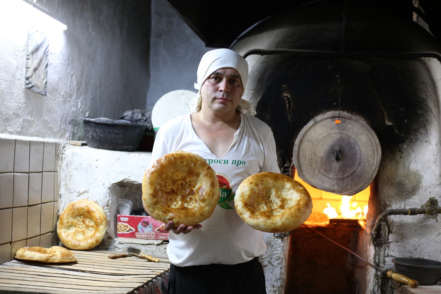 A Tashkent baker holding fresh non from the clay oven