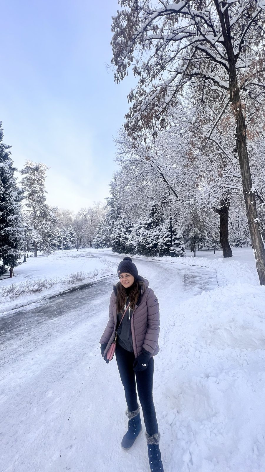A tripper on a snowy path in an Almaty park, trees heavy with snow