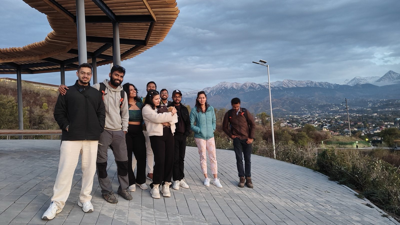 OJ group on an Almaty viewpoint at sunset, mountains behind the city