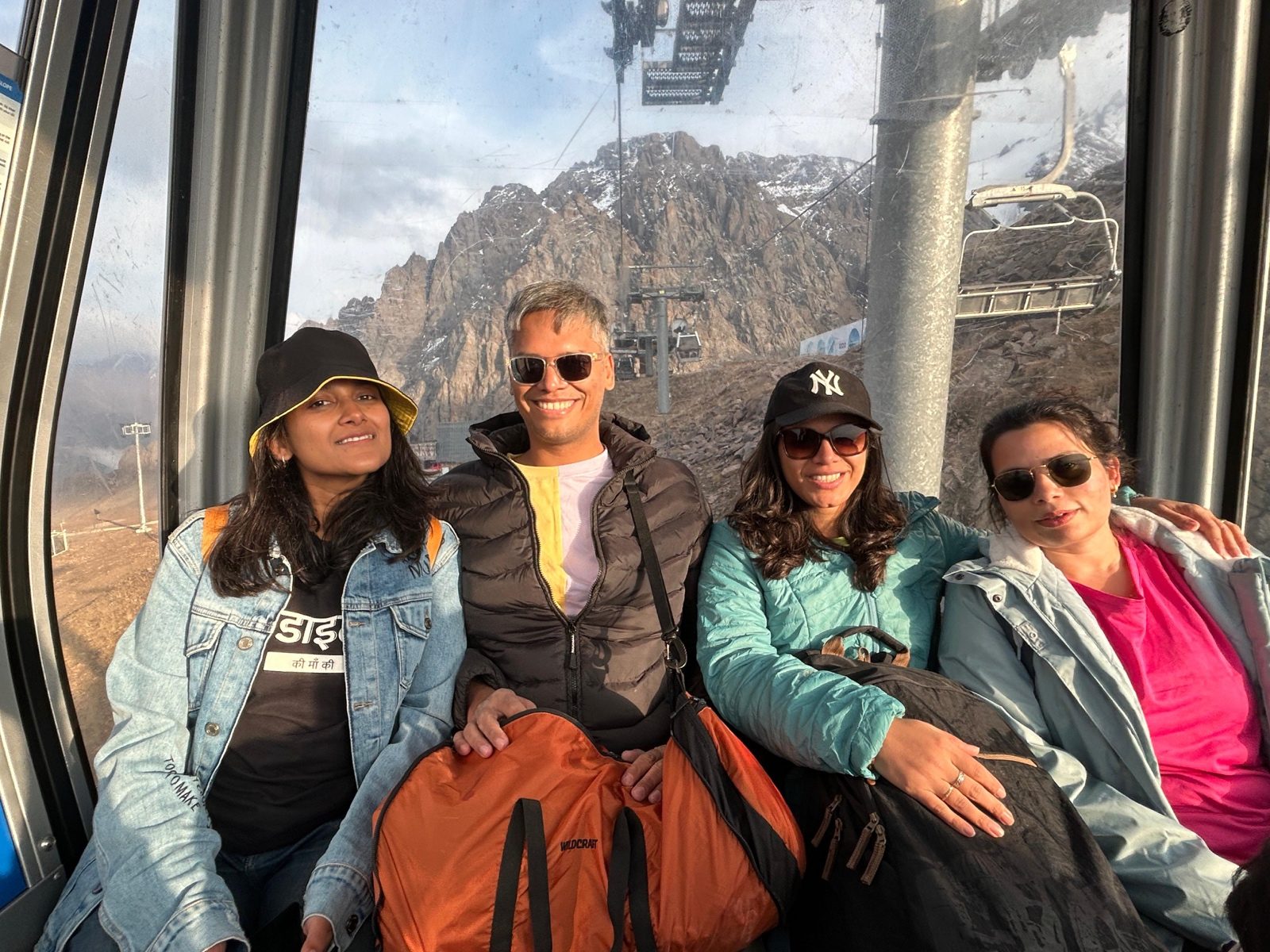Four OJ trippers inside the Shymbulak cable car with mountain peaks through the window