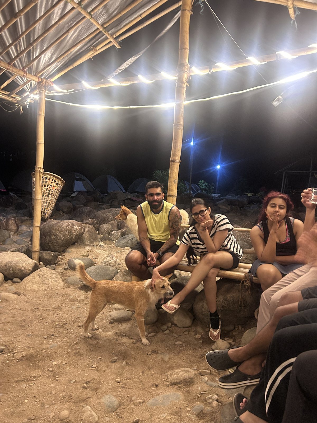 Meghalaya, Day 7, bamboo trek and camping at Shnongpdeng: trippers on a bamboo bench under fairy lights at the camp