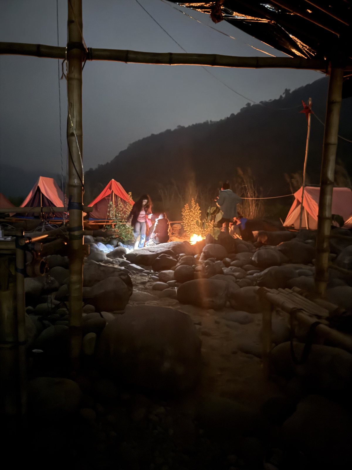 Meghalaya, Day 7, bamboo trek and camping at Shnongpdeng: campfire and red tents at the rocky river camp
