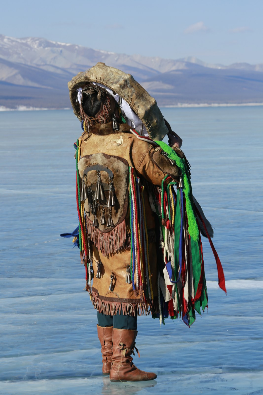 Darkhad shaman in full costume standing on the frozen lake