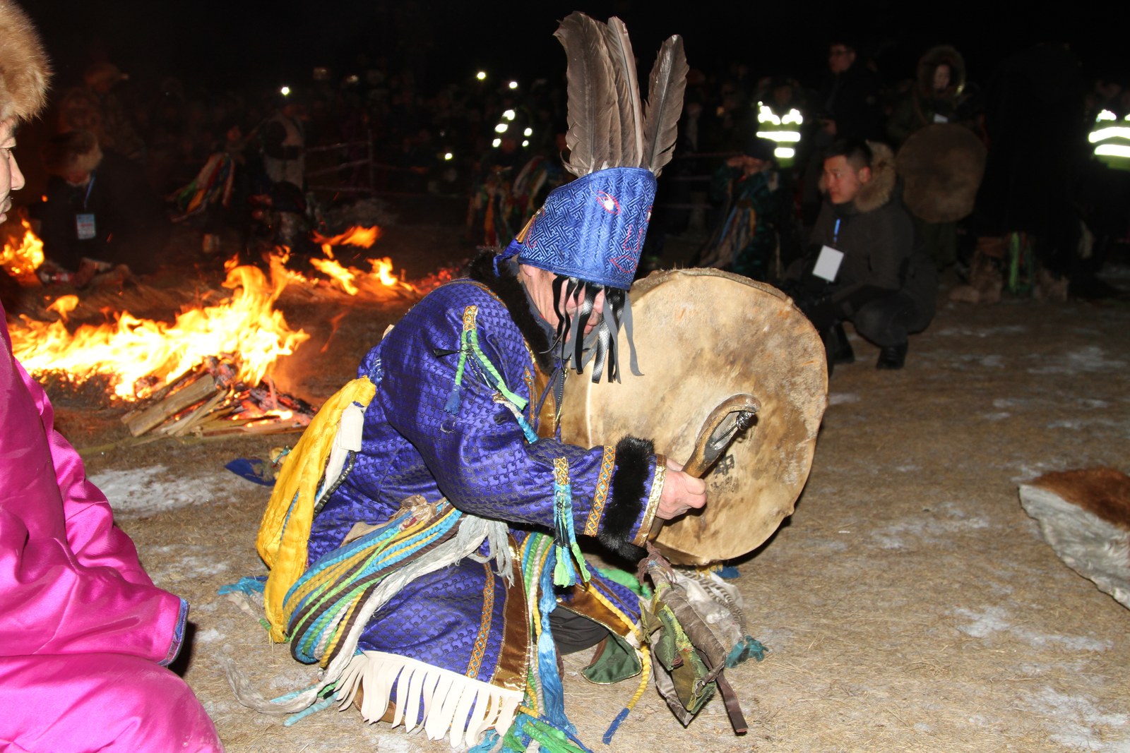 Shaman with a drum beside the fire at night during the Khuvsgul fire ritual