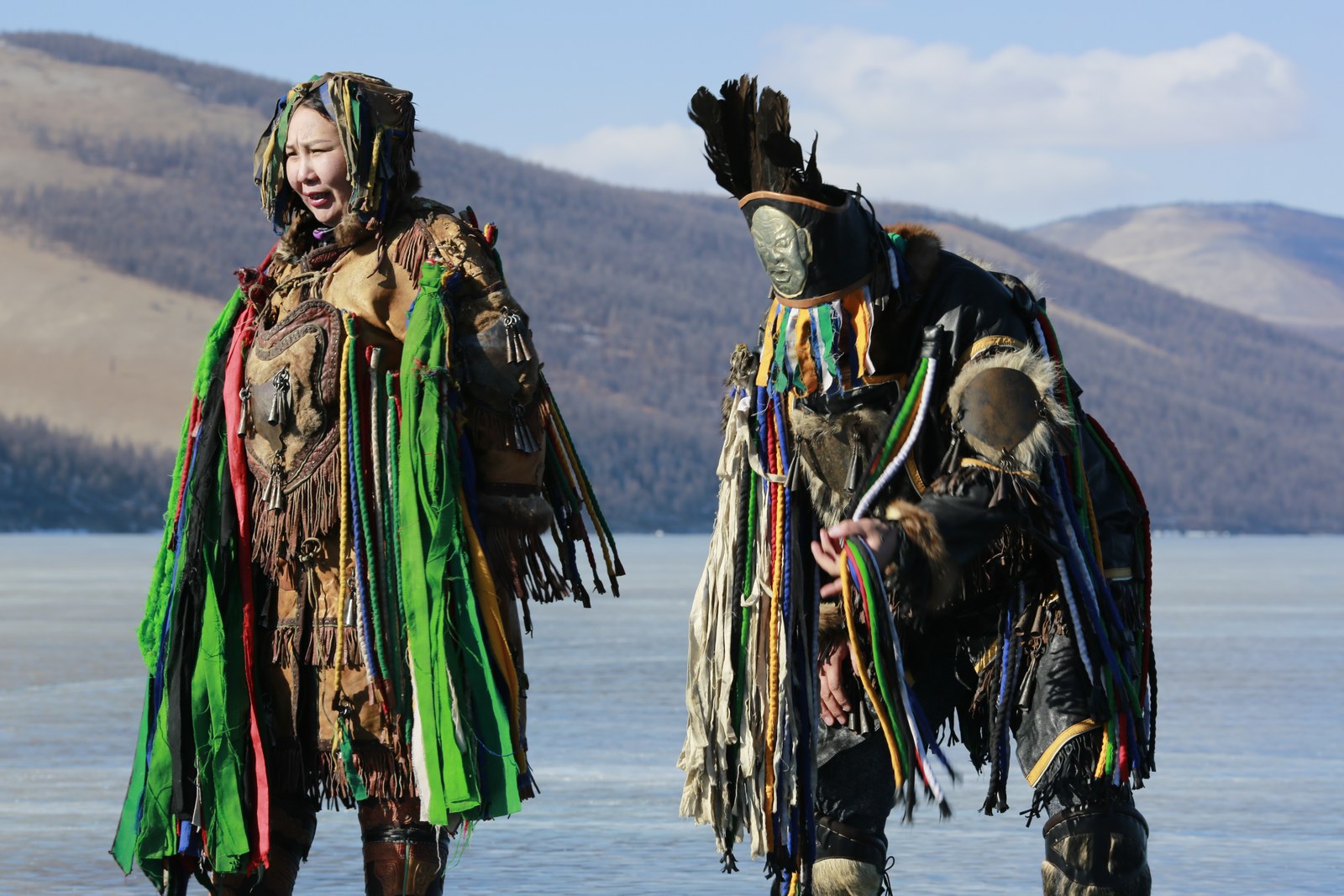 Two shamans on the frozen lake before the ritual, hills behind