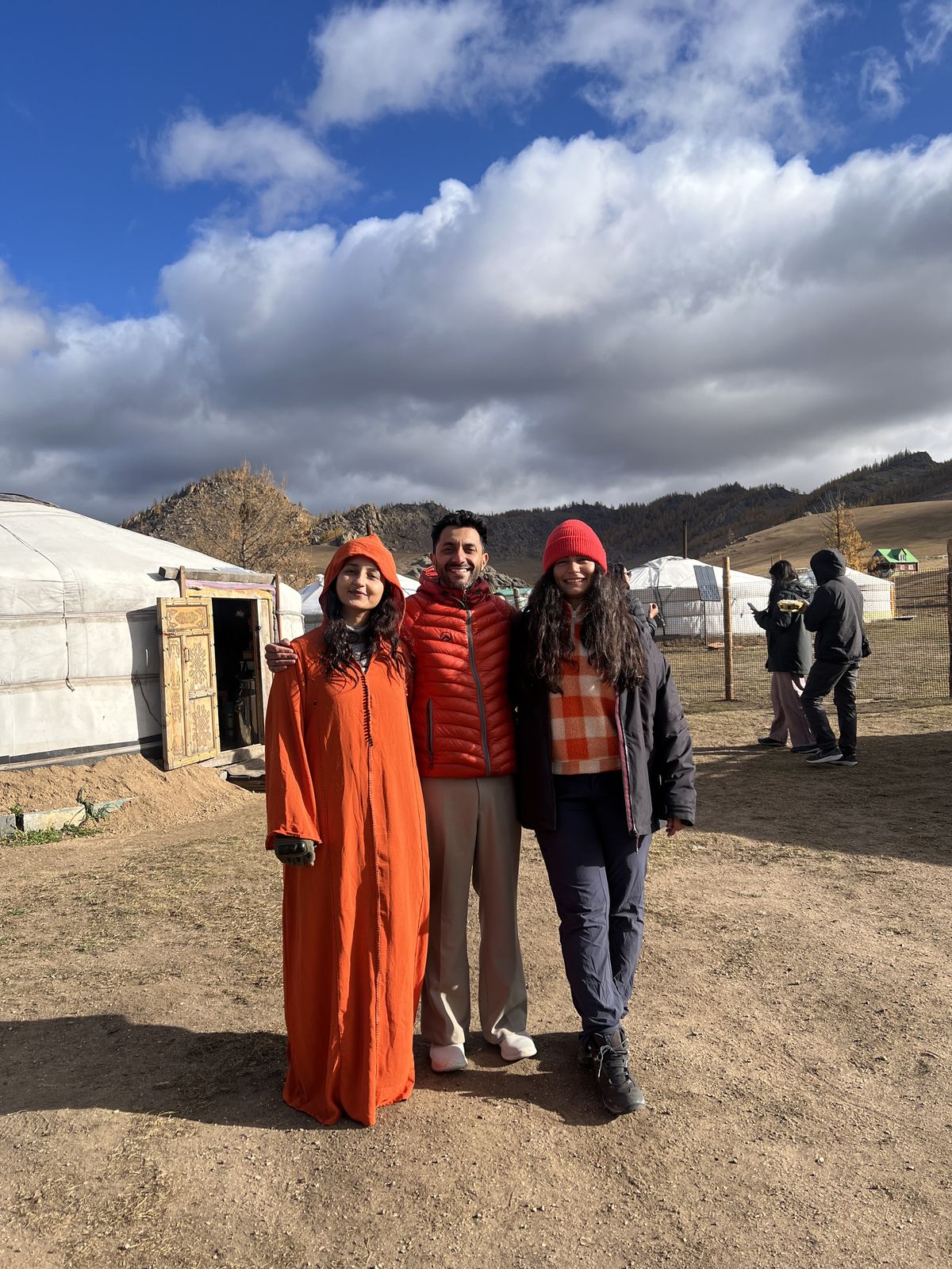 Three travelers in orange deels outside the gers