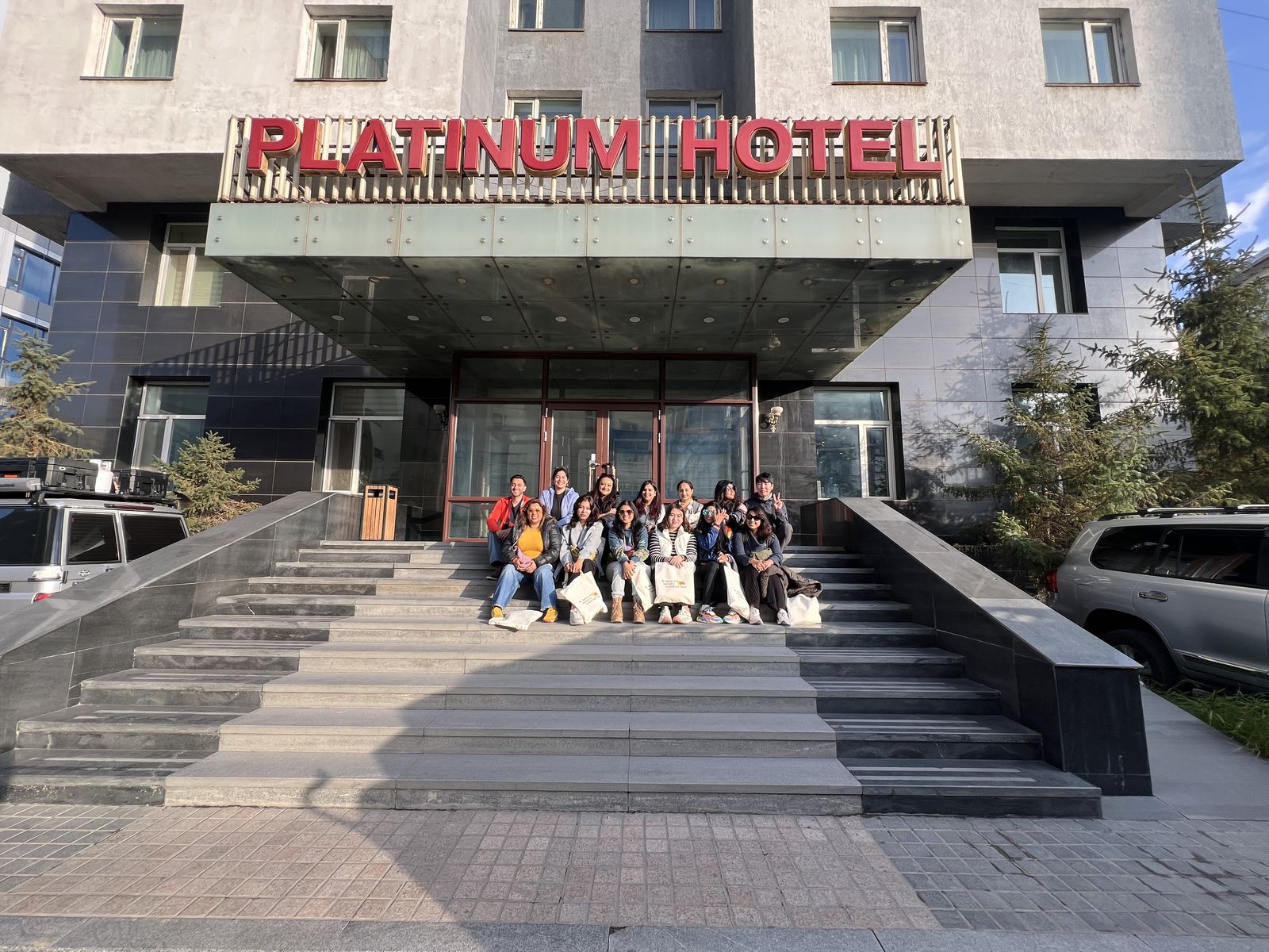 The group sitting on the steps of the Platinum Hotel in Ulaanbaatar