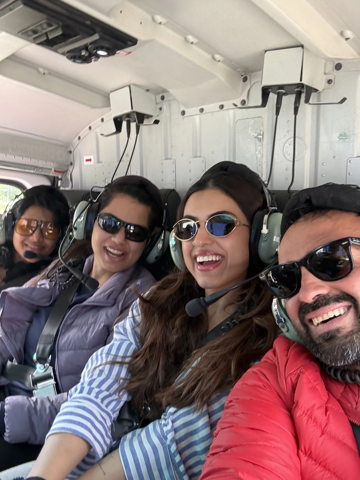 Four OJ trippers laughing inside a helicopter with headsets on
