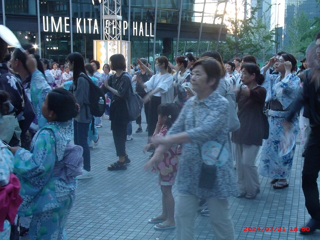 People in yukata dancing the Bon Odori around a tower at an Obon festival in Japan