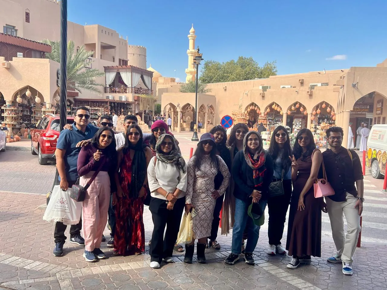 The OJ crew posing in the square at Nizwa Souq, minaret and arches behind