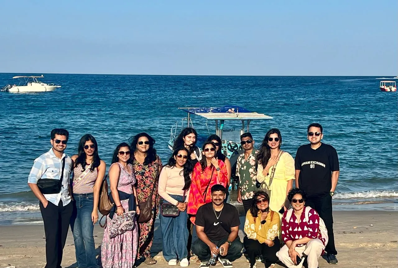 The whole OJ crew on the beach with the boat behind them