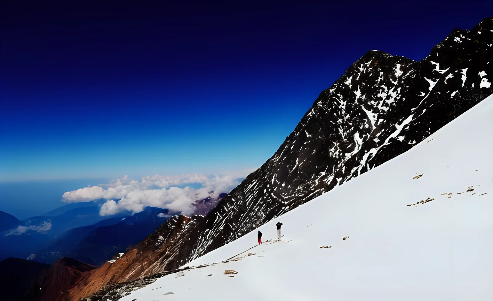 Trekkers on a snow slope above the clouds