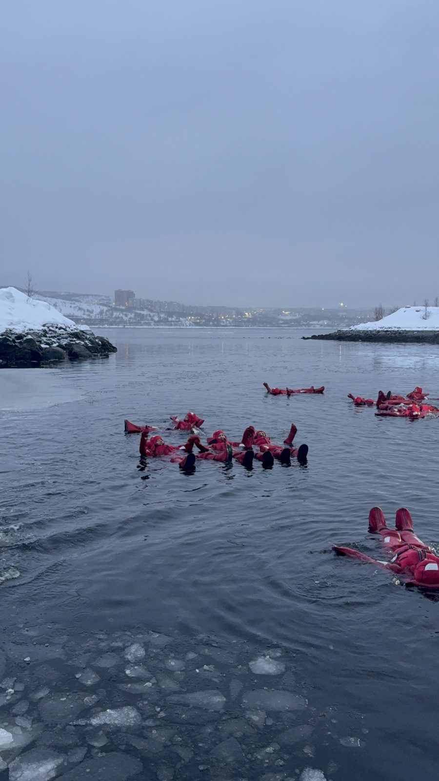 Floating in the Arctic sea in red survival suits