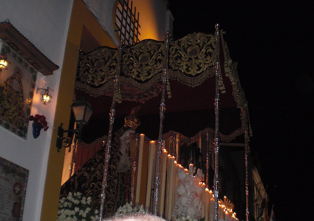 A Semana Santa procession with a float and hooded penitents in Seville, Spain